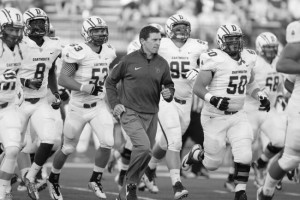 Head coach Buddy Teevens jogs onto the field with his team at a game in 2015.